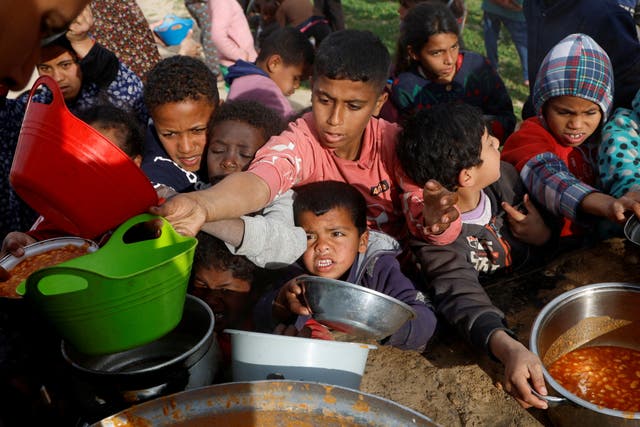 <p>Palestinian children receive food cooked by a charity kitchen during the fasting month of Ramadan in Khan Younis, Gaza</p>